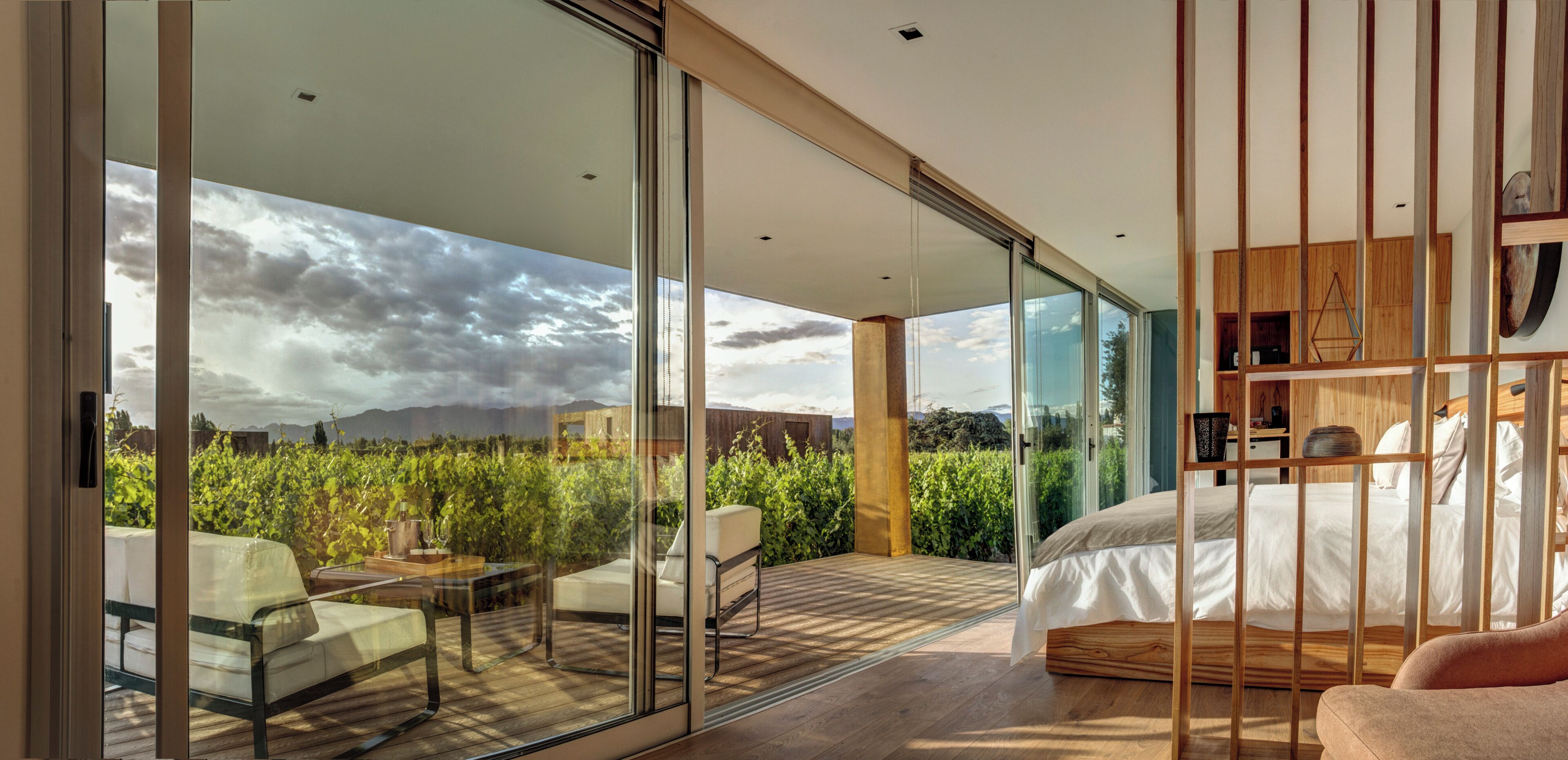 Une chambre moderne avec un grand lit, une porte vitrée donnant sur un balcon et une vue sur l’extérieur.