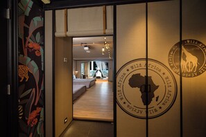 A hotel room with a bed, a desk, and a view of the city.