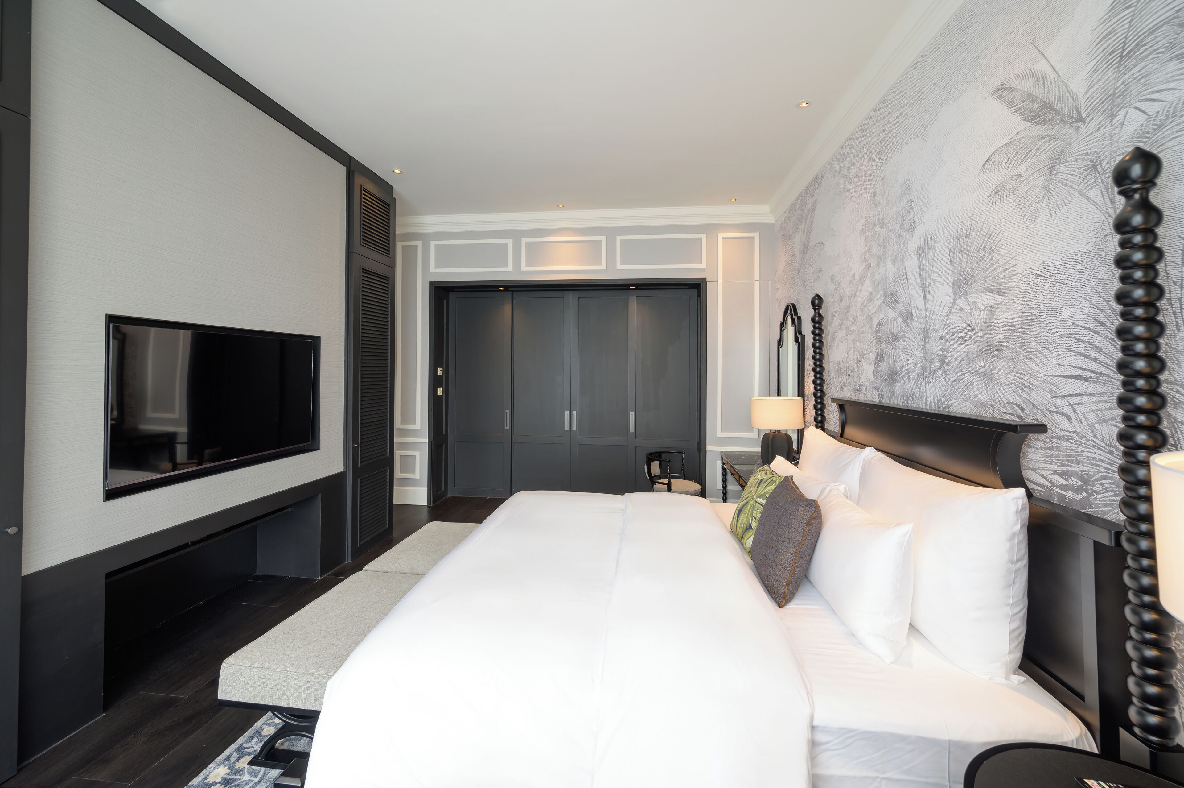 Una camera d'albergo moderna con un letto grande, una TV a schermo piatto montata a parete, un armadio e un murale decorativo.