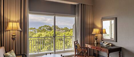 A hotel room with a large window, a bed, a desk, and a chair.