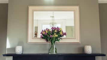A framed mirror on a wall with a vase of flowers in front of it.