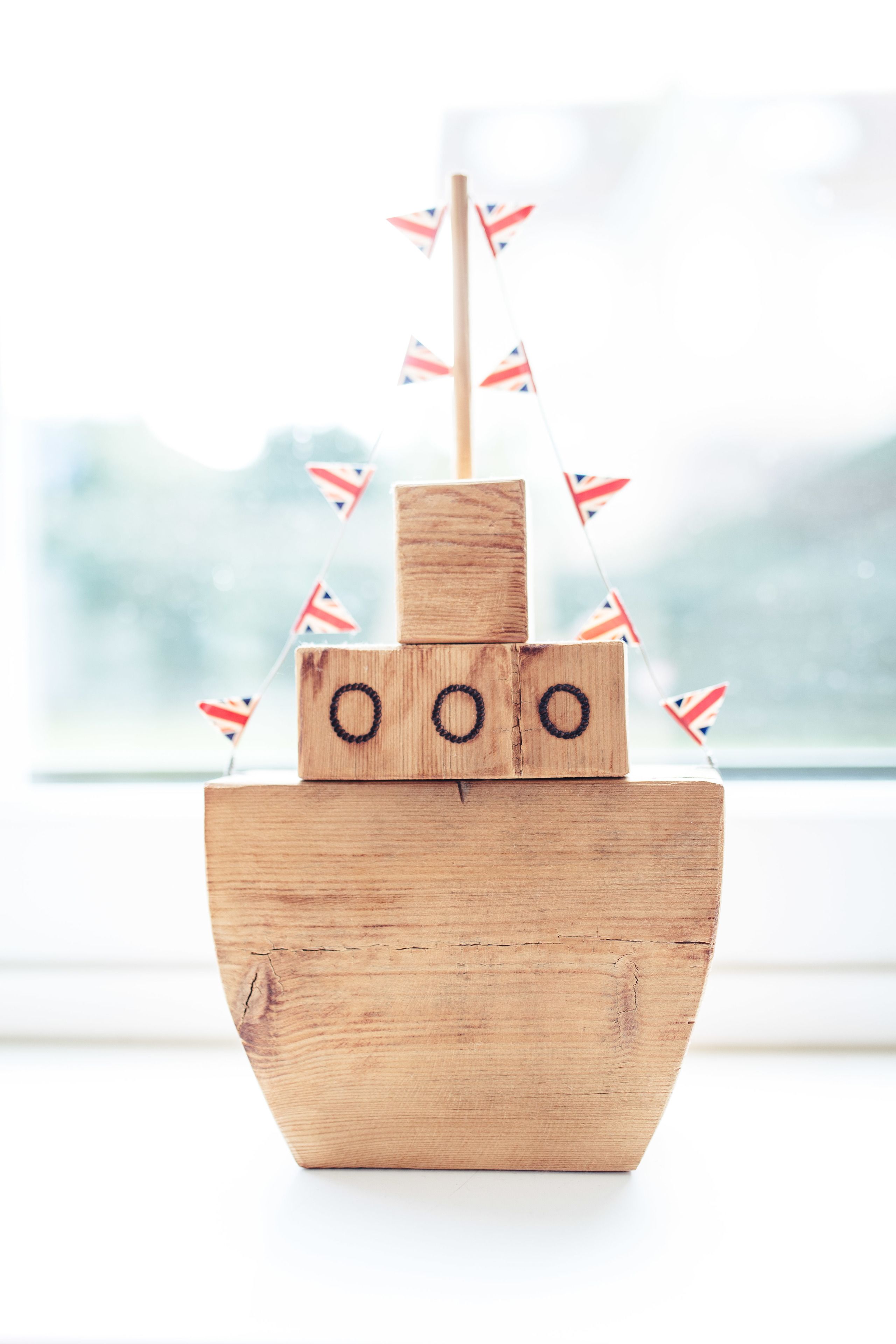 Un modelo de barco de madera con banderas, colocado en un alféizar.