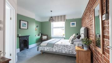 Ein Schlafzimmer mit Bett, Fenster, Kamin und Backsteinwand.