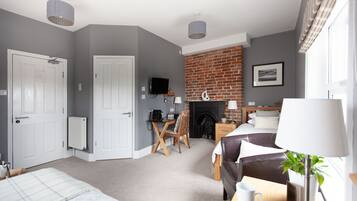A modern hotel room with a fireplace, a dining area, and a cozy seating area.