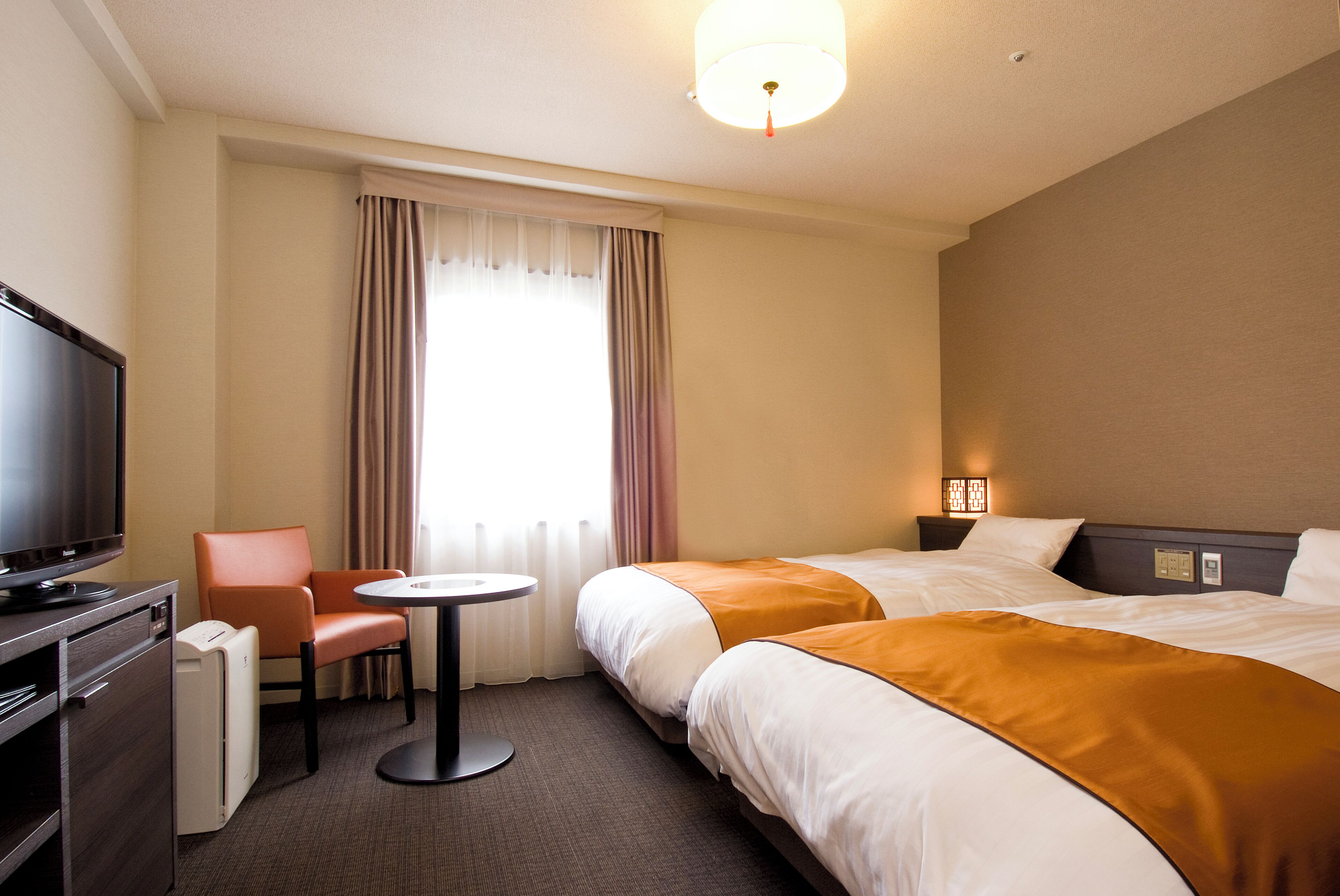 Een hotelkamer met twee bedden, een televisie, een bureau en een stoel.