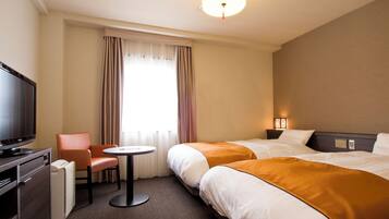 Een hotelkamer met twee bedden, een televisie, een bureau en een stoel.