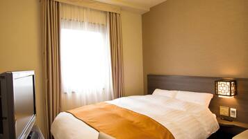 Una habitación de hotel con una cama, un televisor, una mesita de noche y una lámpara.