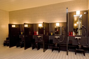 Een openbaar toilet met meerdere cabines, elk voorzien van een spiegel, wastafel en handdoekdispenser.