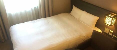 A hotel room with a large bed, a bedside table with a lamp, and a chair.