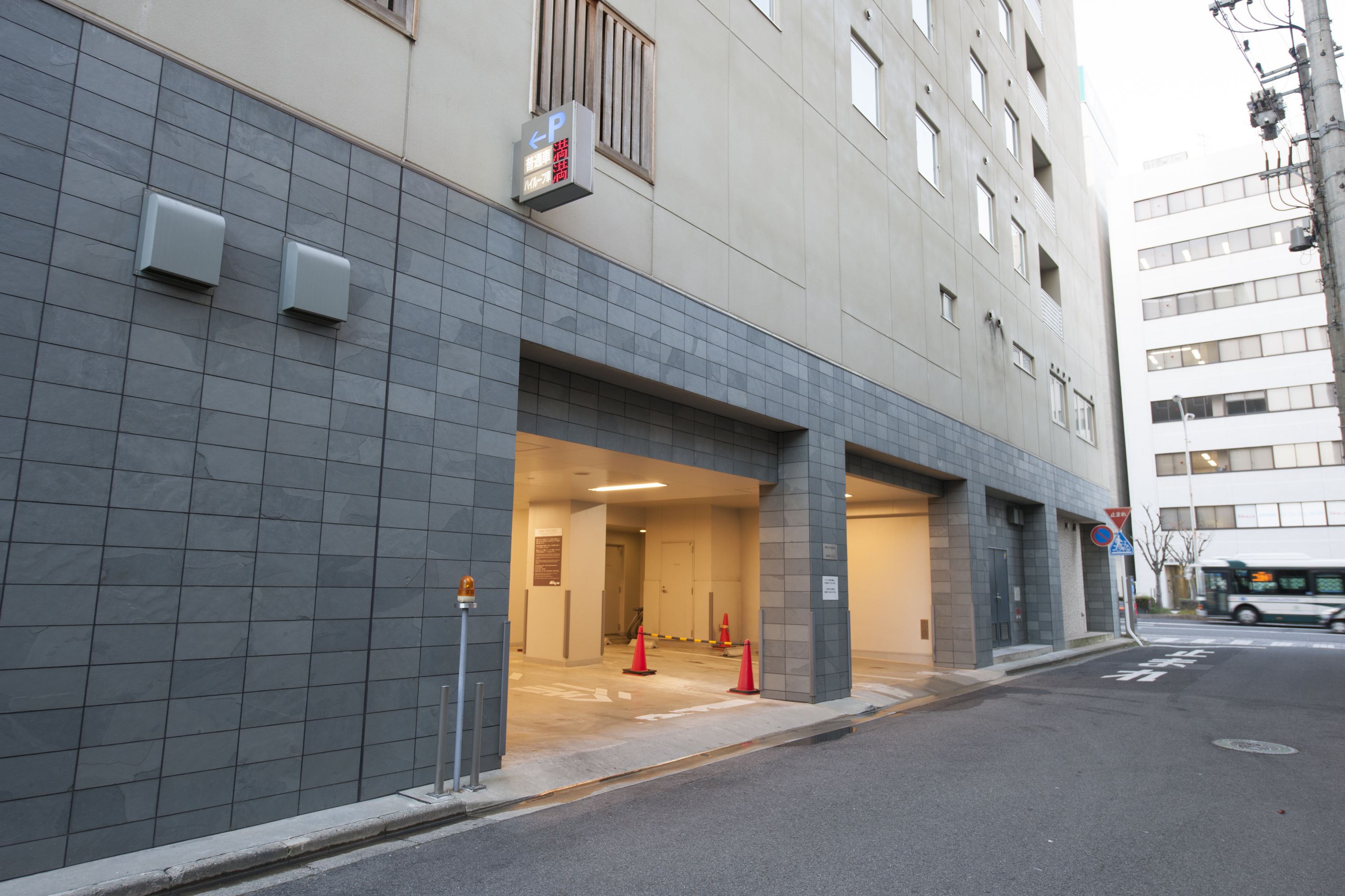 A building with a covered entrance, tiled walls, and a parking sign.