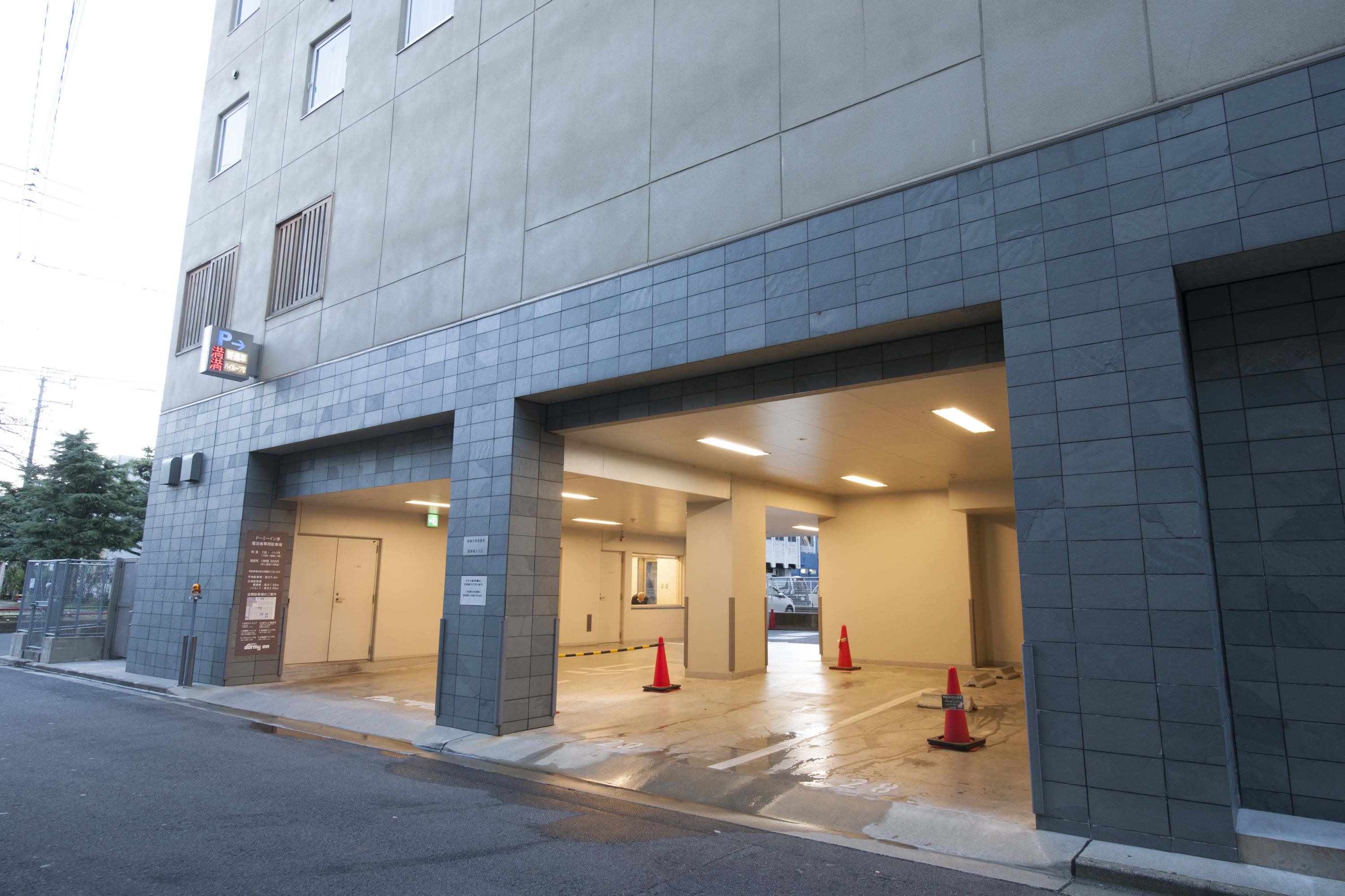 A building with a tiled facade, multiple doors, and a parking sign.