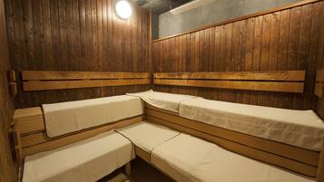 Una sala de sauna con bancos de madera, iluminación en el techo y pared de madera.