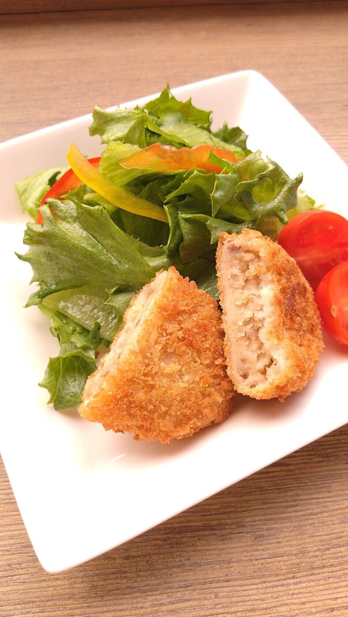 A plate with a salad and two pieces of breaded food.