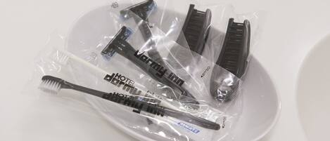 A white plate with a set of grooming tools, including a toothbrush, razor, and comb, all in plastic packaging.