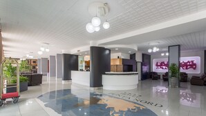 A hotel lobby with a reception desk, seating area, and a world map floor design. - Punta Nord Village & Hotel (Rimini)