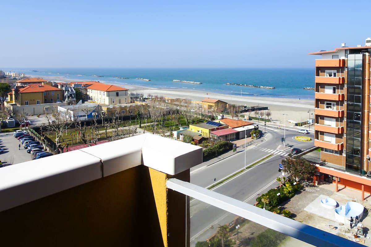 A high-rise building with a view of a beach and a parking lot.