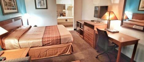 A hotel room with a bed, desk, chair, and a small table.