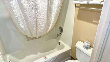 A bathroom with a bathtub, toilet, and a towel rack with folded towels.