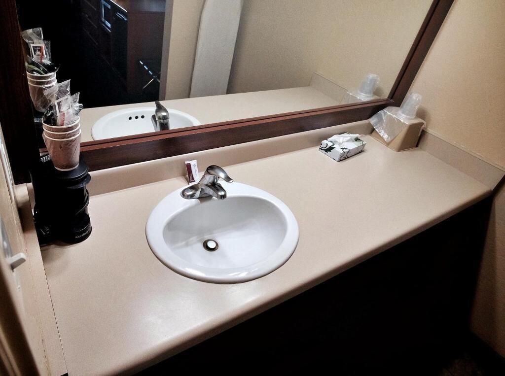 A hotel bathroom with a white sink, a mirror, and toiletries.