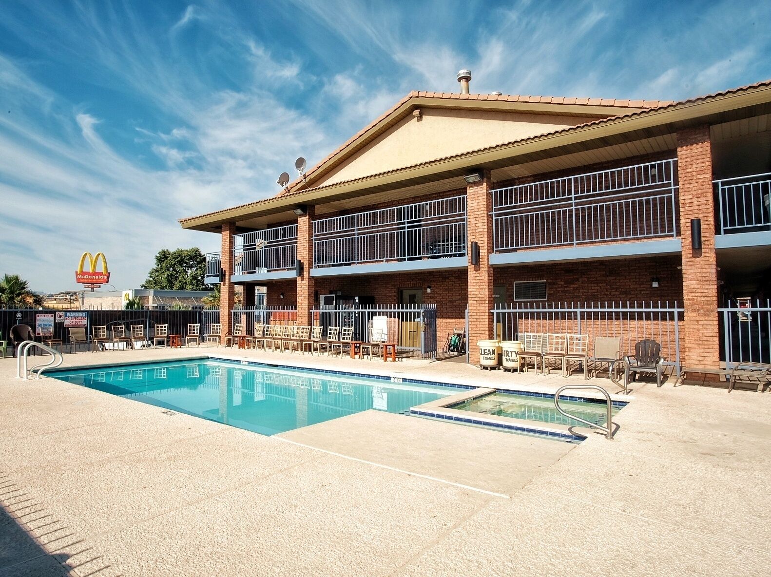 A hotel with a pool, outdoor seating, and a McDonald's sign in the background.