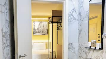 Ein modernes Badezimmer mit Marmorfliesenspiegel, einem weißen Waschbecken und Holzboden.