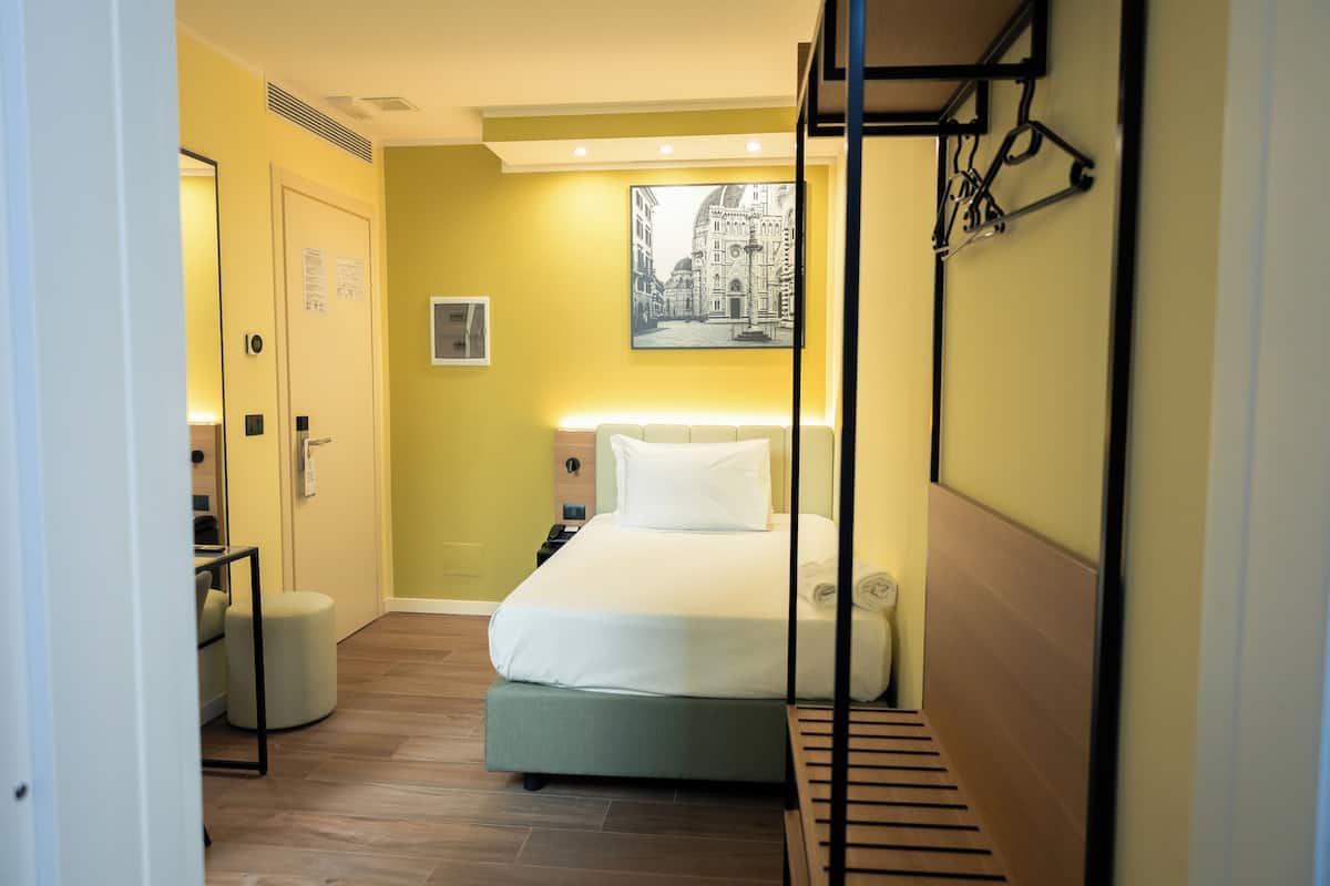 A hotel room with a bed, bedside table, and a wall-mounted artwork.