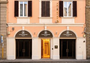 Fachada de un hotel con tres entradas, cada una identificada con el logotipo y el nombre del hotel.
