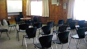A room with wooden walls, a whiteboard, and multiple black chairs arranged around tables.