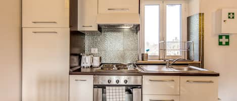 A modern kitchen with stainless steel appliances, a tiled backsplash, and a window with blinds.