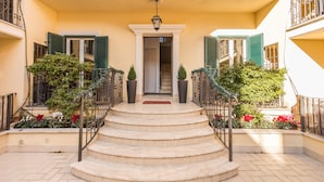 A building with a central entrance, steps leading up to it, and a balcony with railings. - Aurelia Vatican Apartments (Rome)