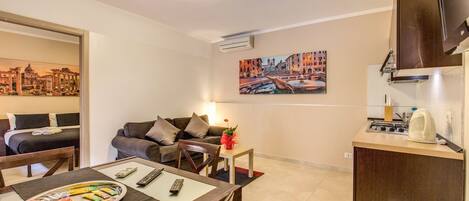 Una habitación de hotel compacta con comedor, kitchenette, sofá y cama.