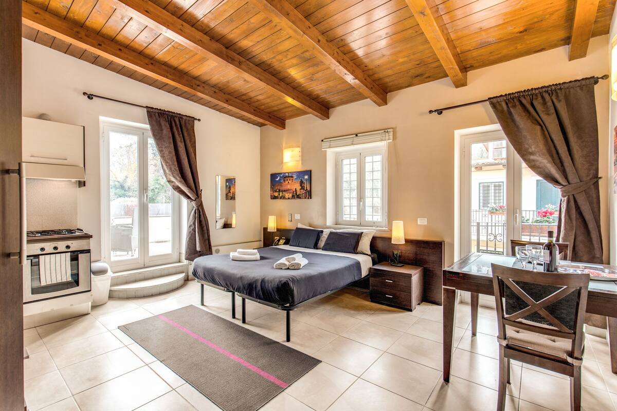 A bedroom with a bed, bedside tables, a desk with a chair, a window, and a view of the outside.