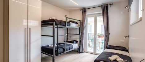 Una habitación con literas, un escritorio y teléfono, y un ventanal corredero que da a un balcón.