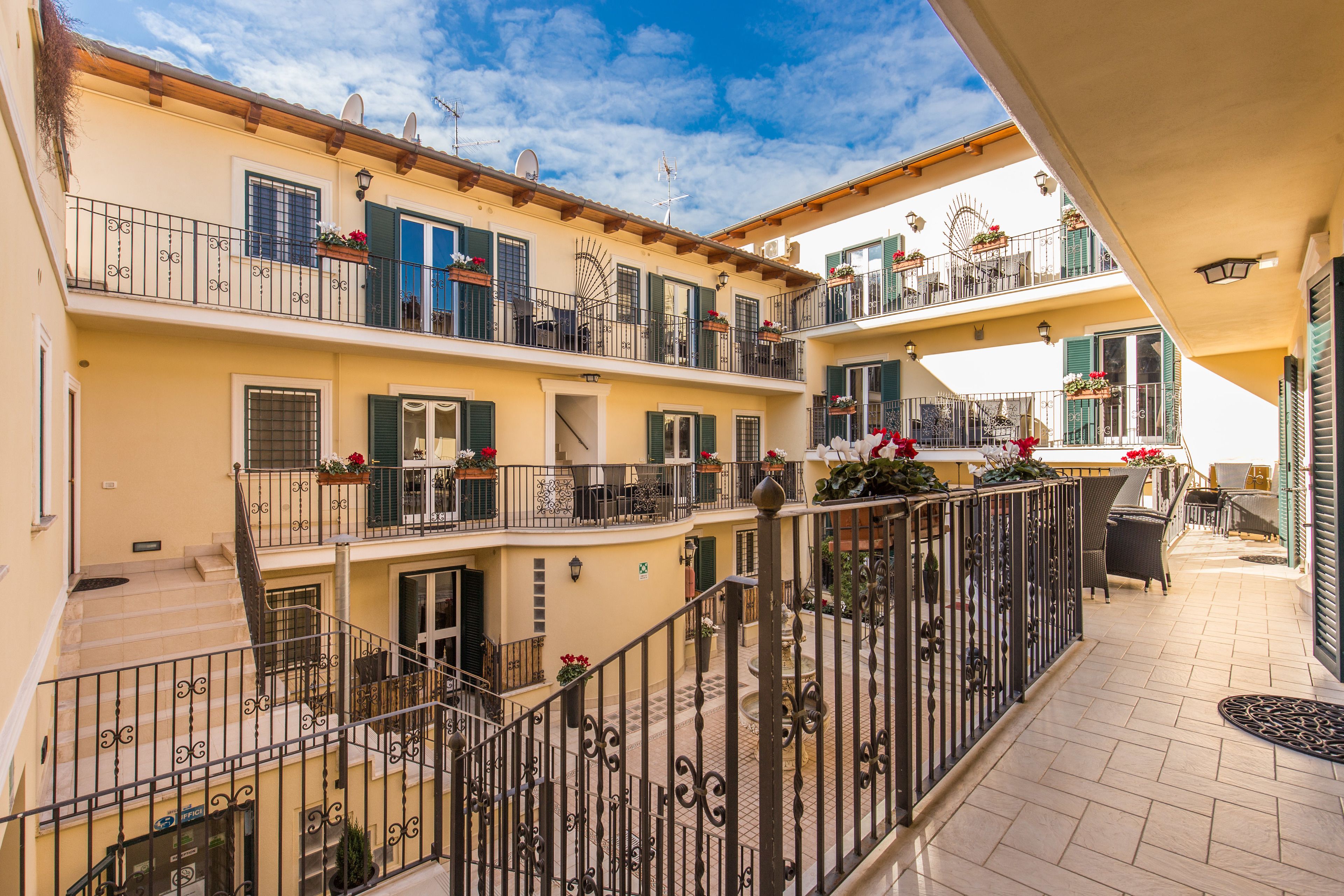 A multi-story building with balconies, outdoor seating, and potted plants.