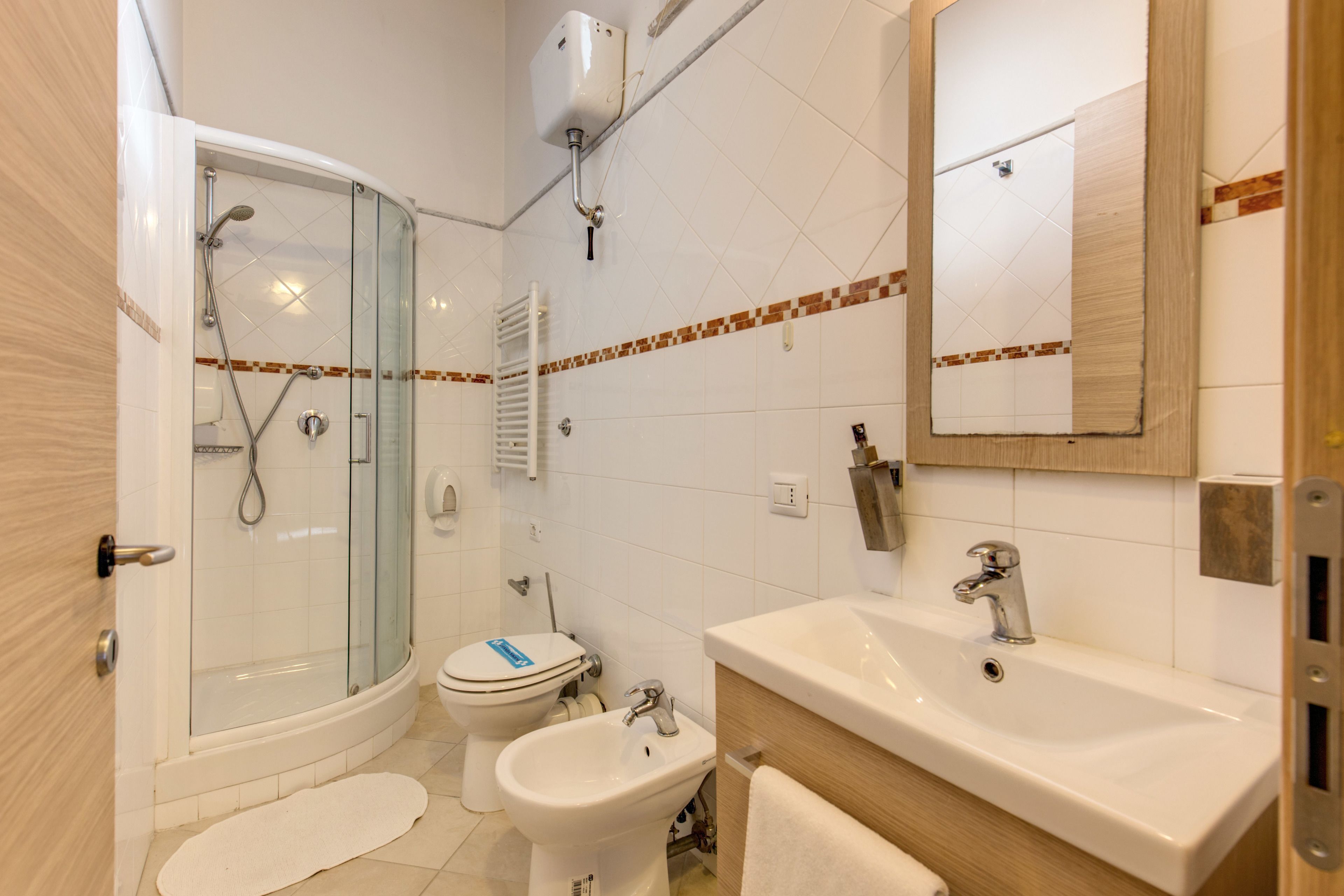 Un baño moderno con cabina de ducha de vidrio, un lavamanos blanco y un inodoro.