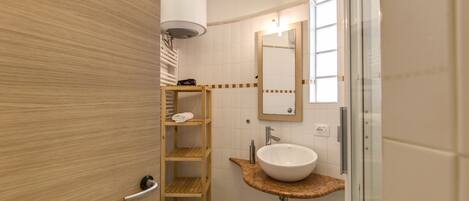 A modern bathroom with a wooden vanity, a white sink, a toilet, and a glass shower enclosure.