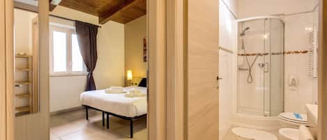 A bedroom with a bed, a bedside table, and a nightstand with a lamp.