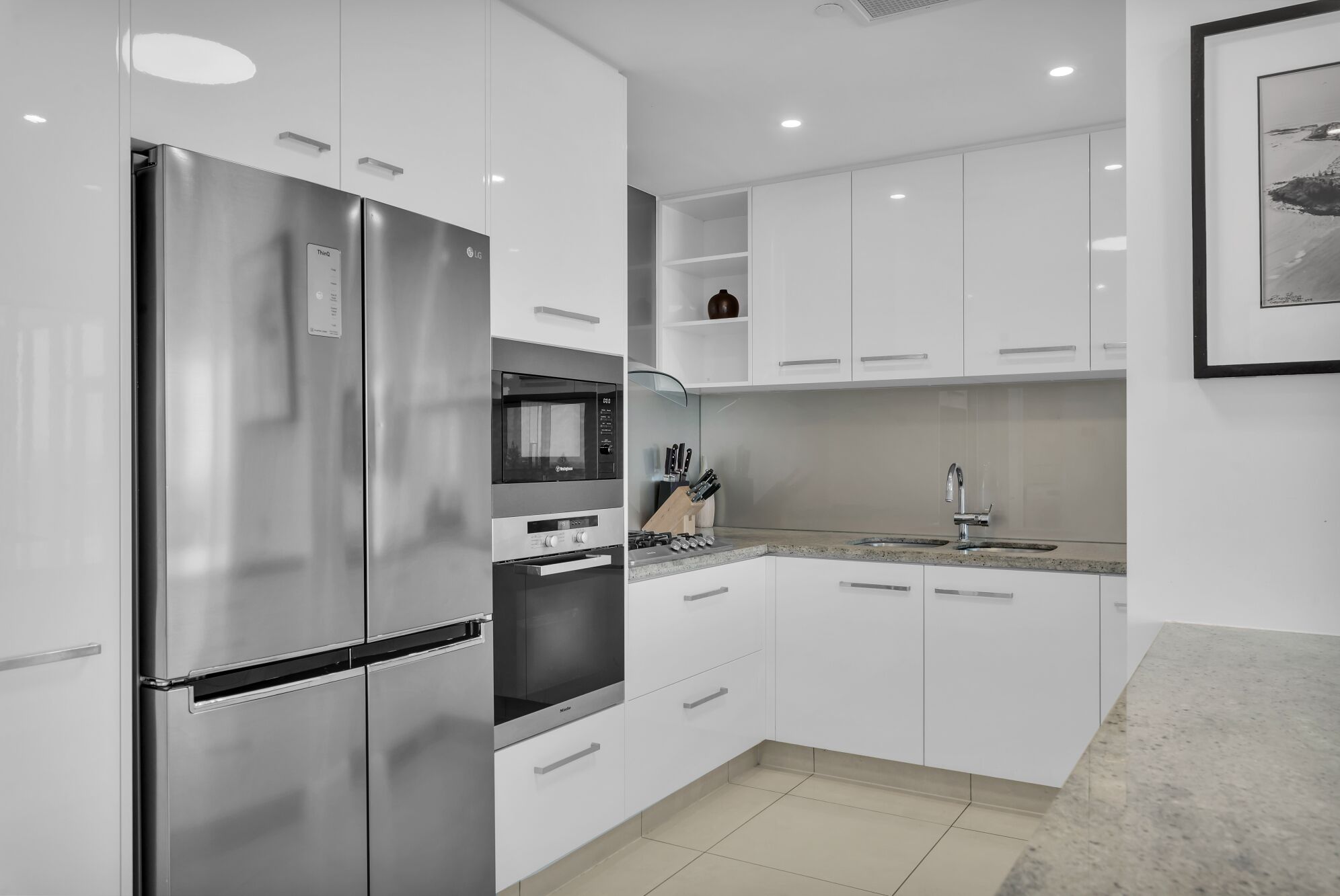 A modern kitchen with stainless steel appliances, white cabinetry, and a granite countertop.