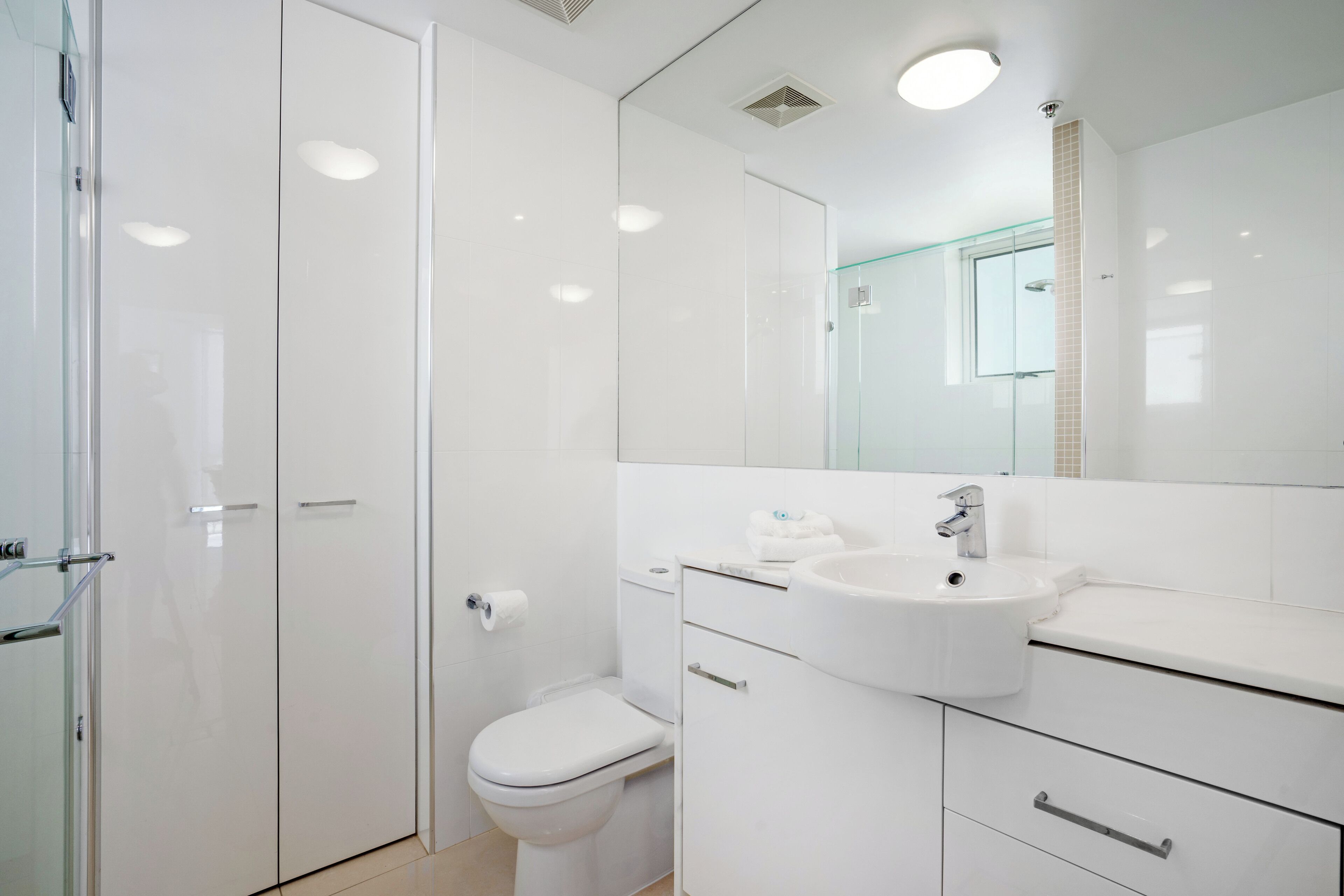 A modern bathroom with a toilet, sink, and glass shower enclosure.