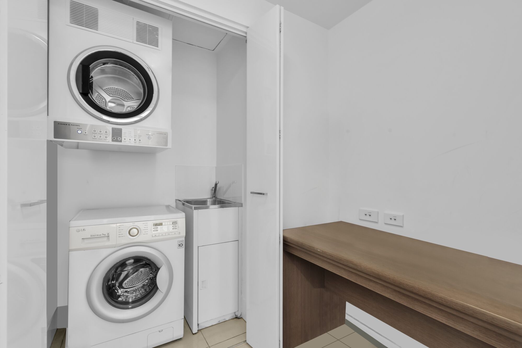 A laundry room with two front-loading washing machines and a sink.