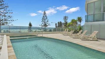 Una piscina al aire libre, sillones reclinables de piscina