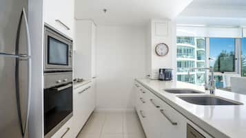 Una cocina moderna con electrodomésticos de acero inoxidable, un lavamanos doble y vistas a un edificio de gran altura.