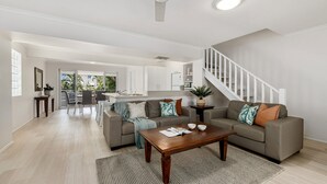 Un salón amplio con sofá, mesa de centro y una escalera que sube a un nivel superior.