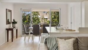 Una sala de estar moderna con un sofá, un comedor con sillas y una mesa, y una encimera de cocina con un lavabo y vasos.