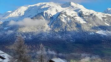 A mountain with snow-covered peaks and a forested valley.