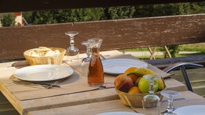 Une table avec des assiettes, une carafe et un panier de fruits, le tout placé devant un paysage de montagne.