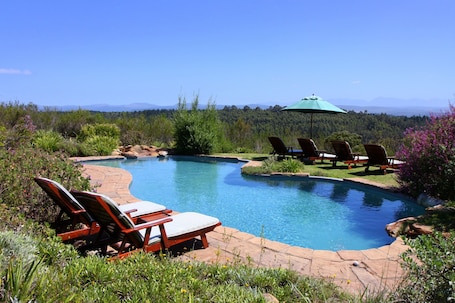 Una piscina al aire libre, sillones reclinables de piscina