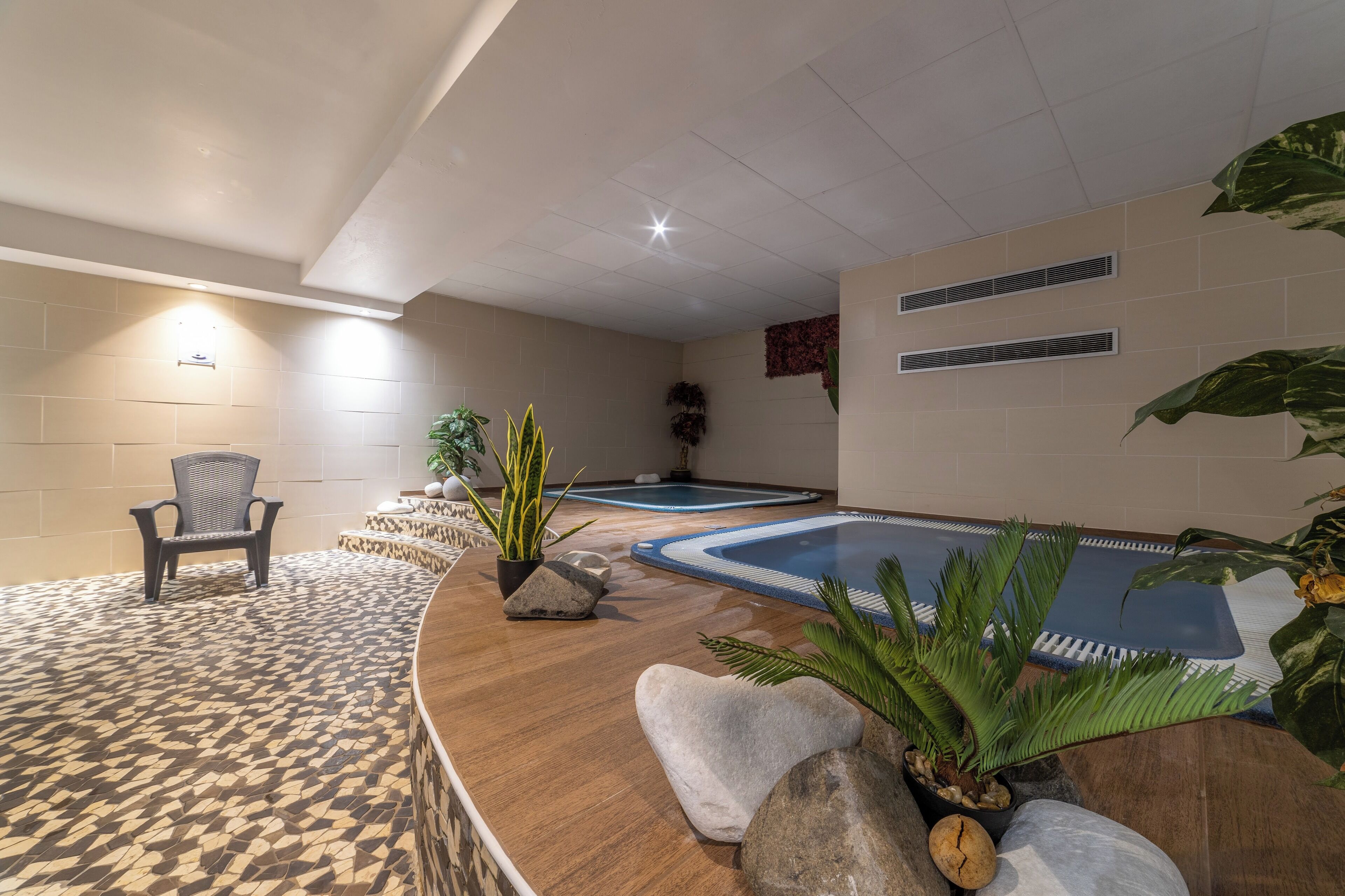 Zona de spa con mostrador de recepción de madera, dos tinas de hidromasaje y una silla.