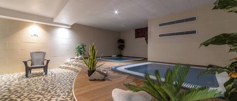 Zona de spa con mostrador de recepción de madera, dos tinas de hidromasaje y una silla.