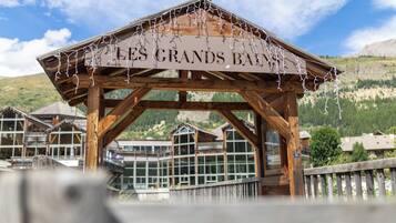 Une structure en bois portant l’inscription « LES GRANDS BAU », avec en arrière-plan une vue sur des bâtiments modernes.